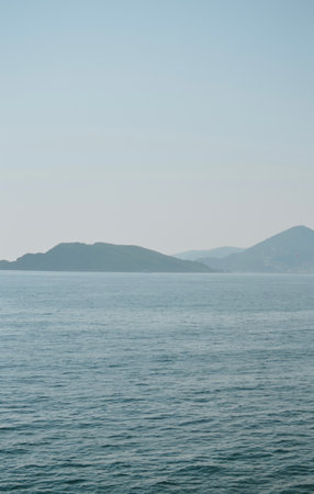view from beach to the sea with waves with the city and mountainsの写真素材