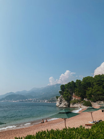 View from beach with rocks and the sea to the tourist town of Budva and mountains in Montenegroの写真素材