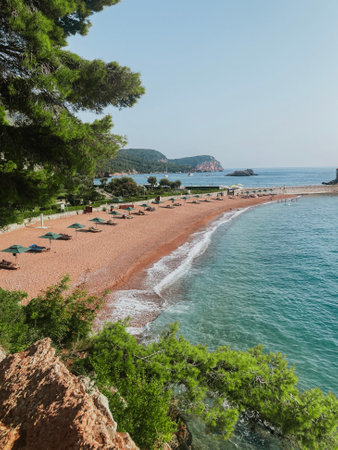 View from beach with rocks and the sea to the tourist town of Budva and mountains in Montenegroの写真素材