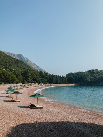 View from beach with rocks and the sea to the tourist town and mountains in Montenegroの写真素材