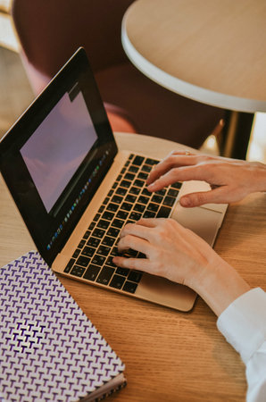 table with laptop with screen for adding your own, woman typing on keyboard, notebook for notesの写真素材