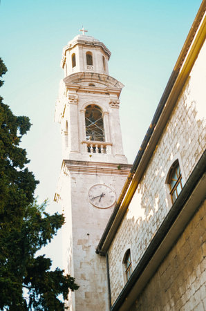 Old built church with huge clock and bell tower in city center of Trogir Croatia summer vacationの写真素材