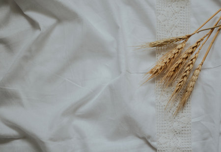 white patterned fabric ribbon with wheat on a background of crumpled white fabricの写真素材