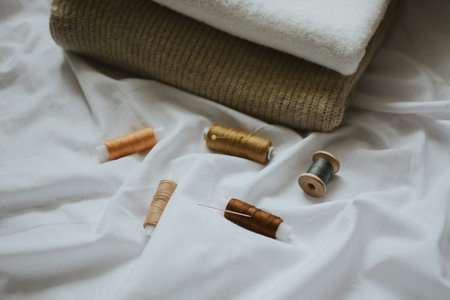 beige shades of thread with needles against the background of delicate colors of fabrics