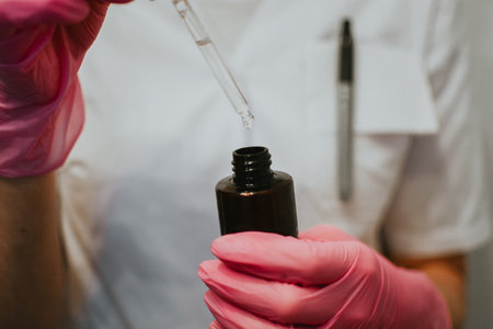 A nurse in a white coat and pink gloves opens a serum close-up to maintain a patients skinの写真素材