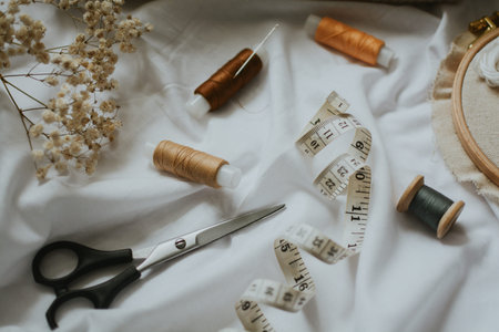 threads of different brown colors with needles, scissors, canvas with floss and measuring tape