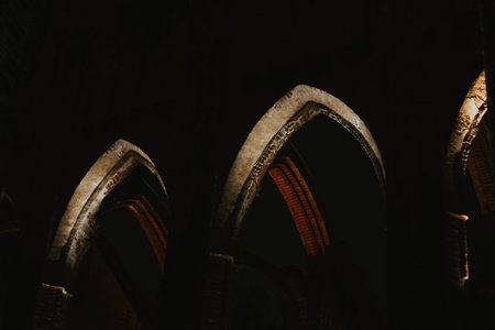 Pointed arch of an old historic brick church with red and white lighting at night in Europe in parkの写真素材