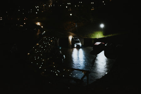 a vehicle in the form of a car is driving along the road to a private house with parking at nightの写真素材