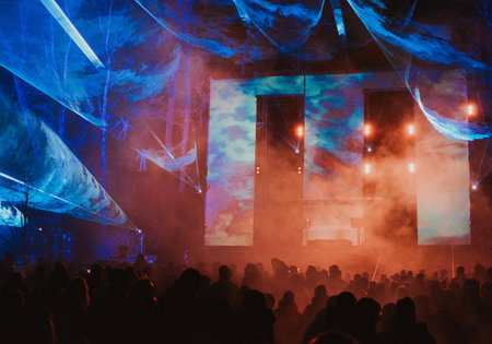 Street concert of a musician in the evening on stage with multi-colored spotlights and a large audience. High quality photoの写真素材