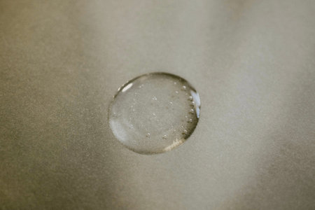 A drop from a cosmetic serum close-up on a gray background.