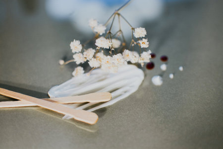 A smear of white cosmetic cream with a large stick and a wooden spatula on a gray background with white flowers.の写真素材
