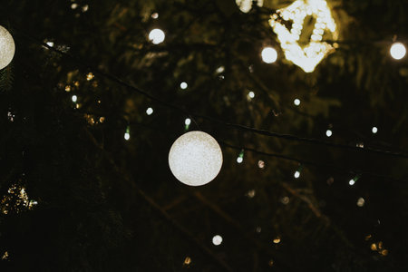 Gold Christmas tree decorations close-up on a street tree with a garland in the Christmas market in the evening. High quality photoの写真素材