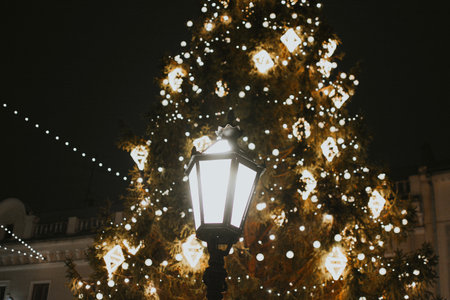 Gold Christmas tree decorations close-up on a street tree with a garland and lantern in the evening. High quality photoの写真素材