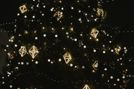Gold Christmas tree decorations close-up on a street tree with a garland in the Christmas market in the evening. High quality photoの写真素材