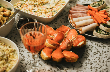 Festive Christmas table with pink wine, appetizers, and salads. In the background, a decorated tree...