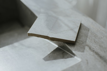 A broken piece of tile lying on a surface. The image showcases a damaged ceramic fragment, ideal for...