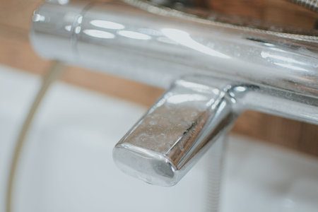 Coated metallic faucet in the bathroom close-up. Plaque and rust due to dirty water.