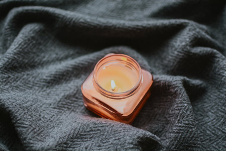 Burned candle against a backdrop of textured gray fabric in a cozy home. Aromatherapy and candles promote good sleep and fresh air in the room. High quality photoの写真素材