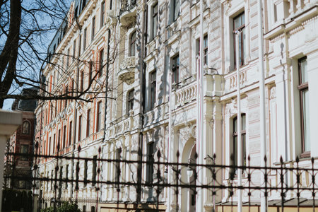 An elegant historic building with a beige neo-Renaissance facade. Rich architectural decoration, arched windows, graceful columns and a balcony, a metal fence. High quality photoの写真素材