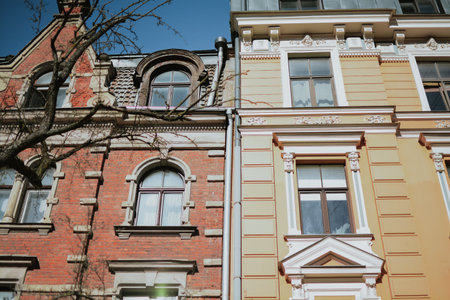 An elegant historic building with a red and yellow neo-Renaissance facade with bricks. Rich architectural decoration, arched windows, graceful columns and a balcony, a metal fence. High quality photoの写真素材