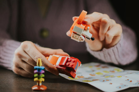 Child assembles multi-colored orange corgi blocks with his own hands. Activity for developing finger motor skills and attentiveness. High quality photoの写真素材