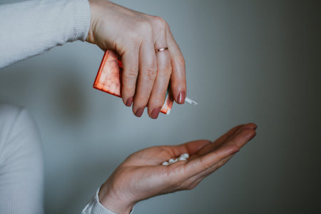 Woman pours orange candy from plastic packaging into the palm of her hand. High quality photoの写真素材