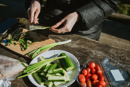 Woman preparing vegetables on cutting board for grilling meat on hike in nature summer close up....