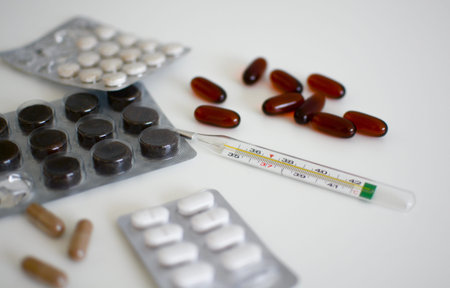 Multi-colored tablets of different shapes with different medical effects and thermometer with...