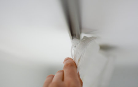 Plastic hooks for curtains close-up. Woman hangs curtains on a cornice in an apartment. High quality photoの写真素材