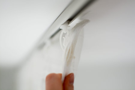 Plastic hooks for curtains close-up. Woman hangs curtains on a cornice in an apartment. High quality...