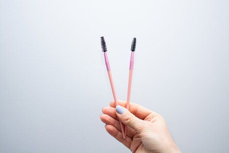 Woman holding pink eyebrow brush close-up. Eyebrow artist paints eyebrows with dye. Body and face care. High quality photoの写真素材