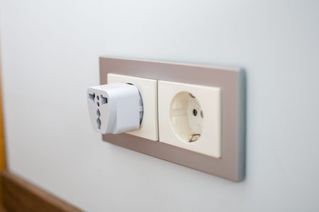 Universal travel adapter in a socket close-up. Adapter for international use of wired equipment...