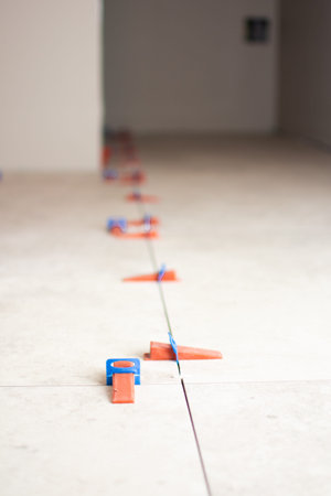 Close-up of ceramic tile installation with tile clips and spacers for grouting. Construction work in...