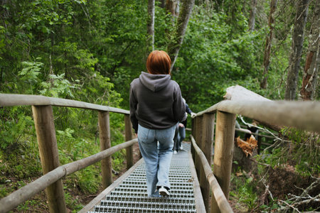 Female hiker goes down the stairs with railings in the depths of the forest. Travel to another...