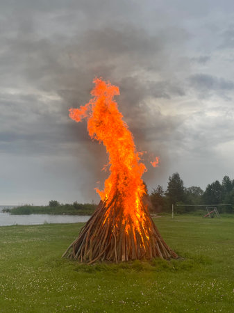 Midsummer bonfire burning in forest by lake on a misty evening. Traditional Estonian Jaanipaev celebration. High quality photoの写真素材