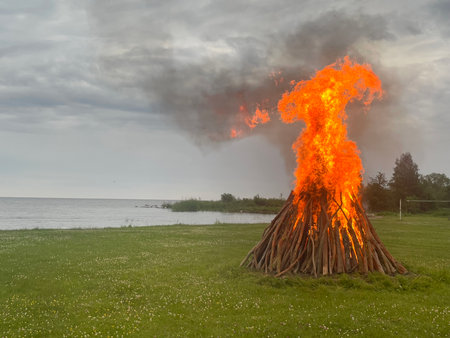 Midsummer bonfire burning in forest by lake on a misty evening. Traditional Estonian Jaanipaev celebration. High quality photoの写真素材