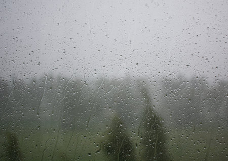 Raindrops on the window during a strong hurricane with wind in nature. High quality photo