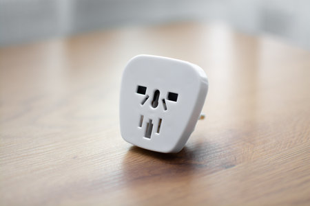 White universal power adapter for electronics on wooden table close-up.の写真素材