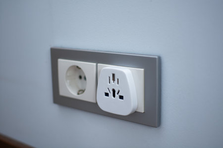 White universal adapter in grey and white wall socket on blue wall, close-up.の写真素材