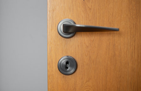 Black door handle and lock with key from wooden door close-up in apartmentの写真素材