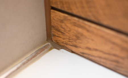 White bathroom meets wooden tile, brown silicone removed from the seam, showing an empty joint
