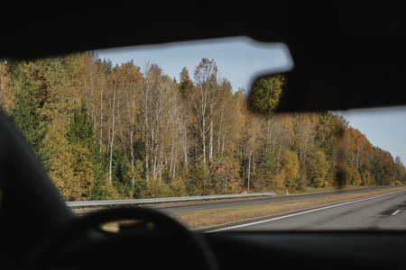 Autumn highway in Belarus, view through a car windshield with forest and clear sky in the distance. High quality photoの写真素材