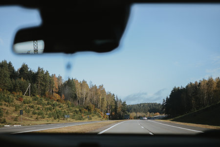 Autumn highway, view through a car windshield with forest and clear sky in the distance. High quality photoの写真素材
