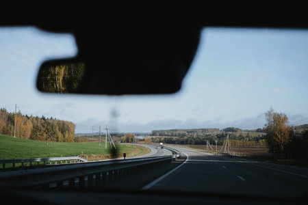 Autumn highway view through a car windshield with forest and clear sky in the distance. High quality photoの写真素材