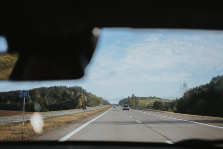 Autumn highway in Belarus, view through a car windshield with forest and clear sky in the distance. High quality photoの写真素材