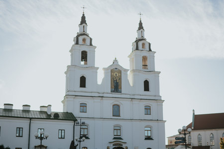 Holy Spirit Cathedral in the Upper Town of Minsk on a sunny autumn day. White church with a green roof and a cross against a blue sky. High quality photoの写真素材