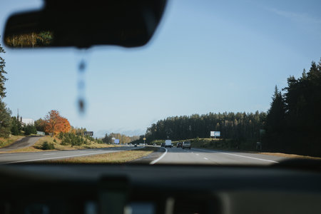 Autumn highway, view through a car windshield with forest and clear sky in the distance.の写真素材