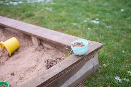 Blue sandbox bucket standing on a sandbox outdoors.