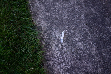 Metal object lying on asphalt next to grass outdoors. High quality photoの写真素材