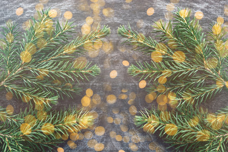 Close up green twig of Christmas tree on wooden vintage background. Yellow shiny cheerful lights. Christmas and New Year holiday. Copy Space and Wallpaperの写真素材